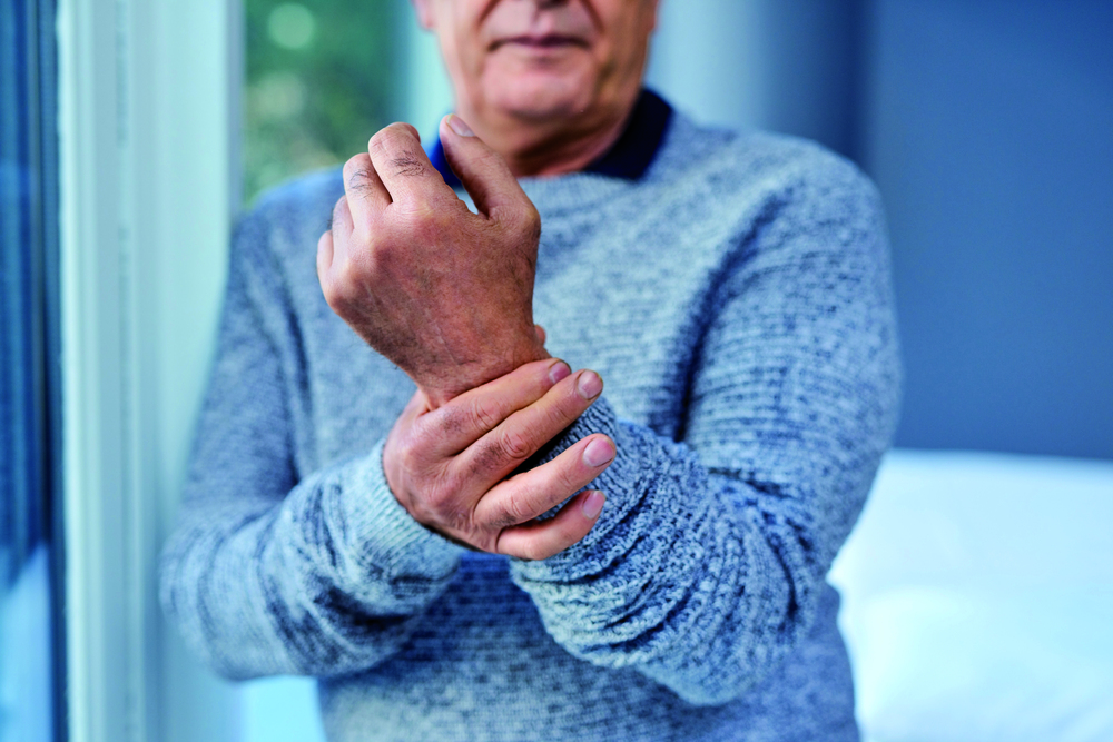Ein älterer Herr greift sich ans Handgelenk